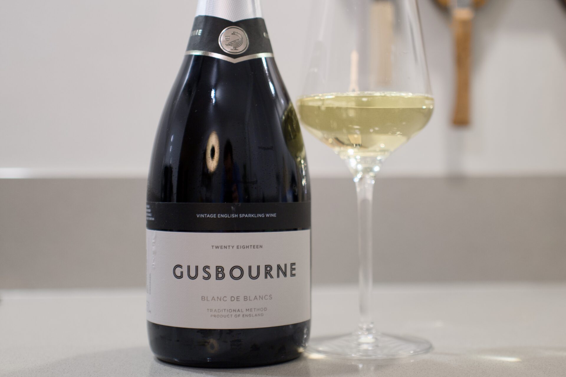 Gusbourne Blanc de Blancs fles naast glas mousserende wijn