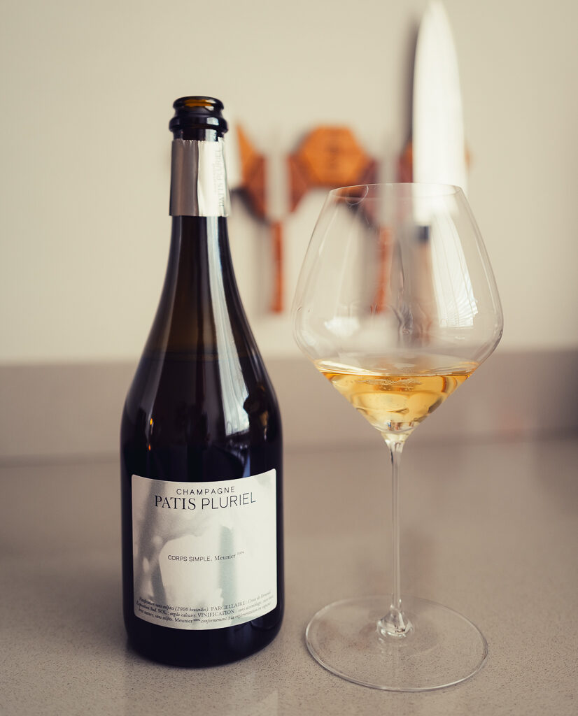 Fles Les Sèves champagne van Patis Pluriel naast een gevuld glas