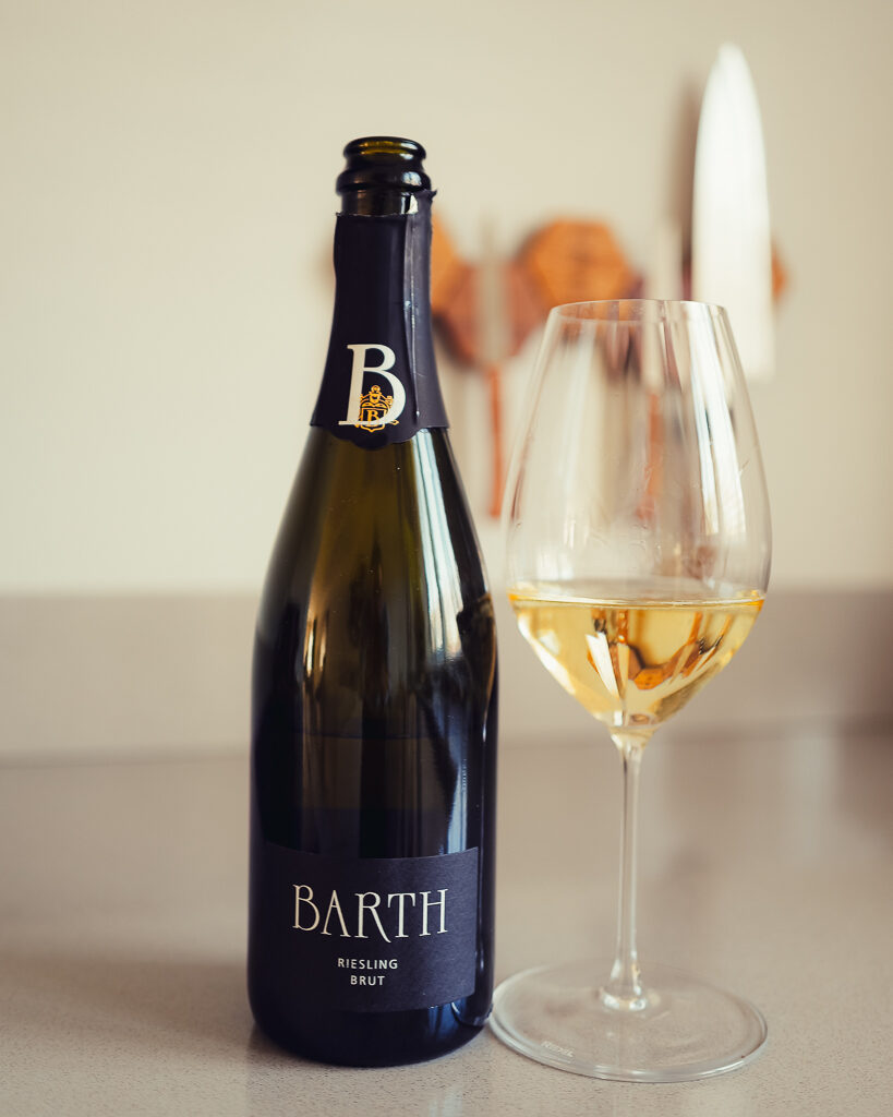 Fles Barth Riesling Brut uit de Rheingau naast een glas mousserende wijn